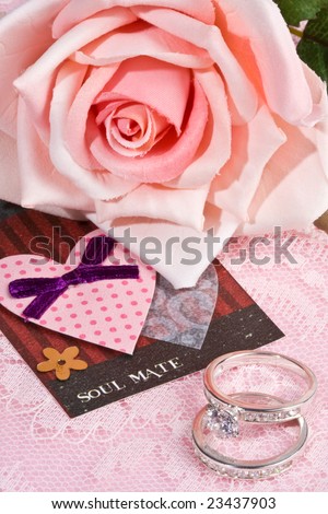 Close up of \'soul mate\' note and rings with pink rose in background