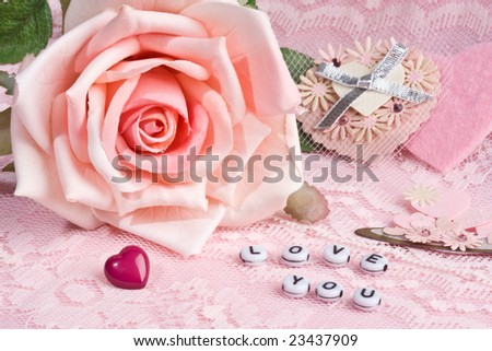 close up of \'love you\' letters with pink rose and hearts in background