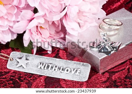 close of up of silver gift box flowers and rings - \'with love\' tag