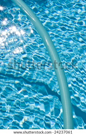 sunlit glistening on surface of pool - with pool filter hose