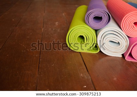 Colorful yoga mats rolled up on a wooden floor.