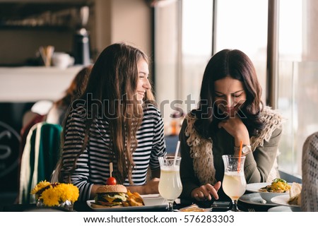 Funny girls meeting up for lunch break to eat delicious food and have a break. Girls fooling around and experiencing new hair-dos thinking about make-over or making change in style.