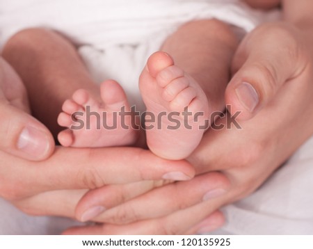 A father hold the the feet of his new born son Focus on right feet