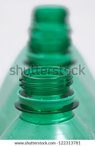 A picture of three green  PTA plastic bottles. Picture has short focus