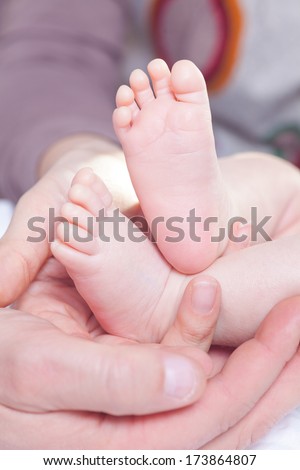 High key picture of hands holding feets of a new-born child.