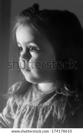 A cute young girl is looking television.She is looking very interested in.Oicture is black and white.