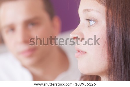 A young women is thinking about something. Man is sitting byside defocused.