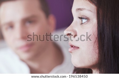 A young women is thinking about something. Man is sitting byside defocused.