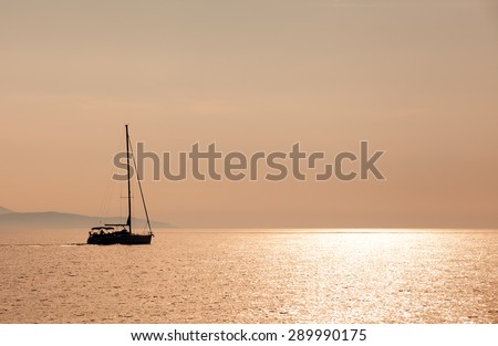A sailboat is cruising in the croatian sea on sunset. Coast of an island in the background.