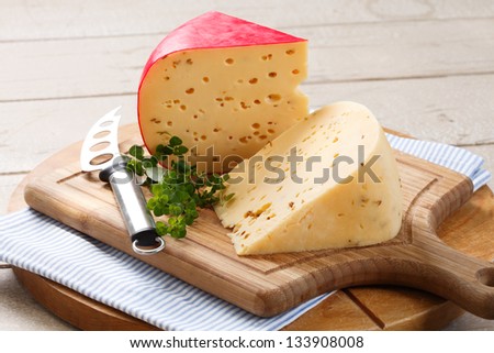 tantalizing gouda cheese and cheese knife on rustic looking wooden cutting board