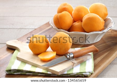 fresh delicious yellow peaches in an antique white bowel on wooden board with some peeled peaches in the fore ground