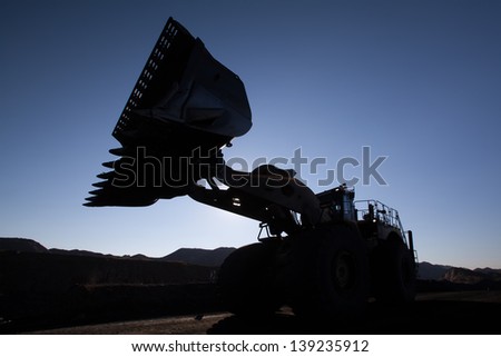 beautiful image of front loader working on a mine at sunrise