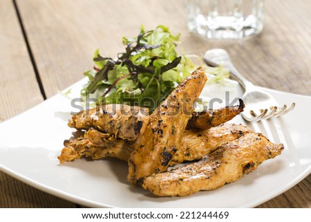 Chicken strips, on a white square plate with a side salad