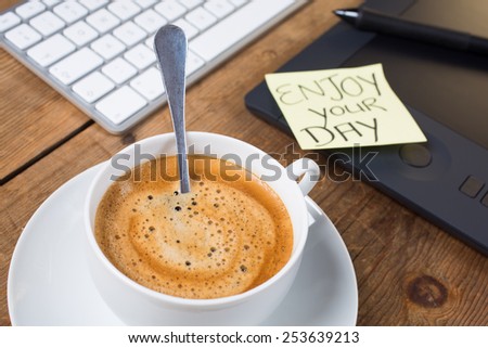 Cup of hot delicious coffee with computer keyboard on a rustic table and stay enjoy your day note