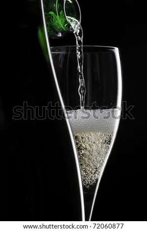 pouring champagne in glass on black background