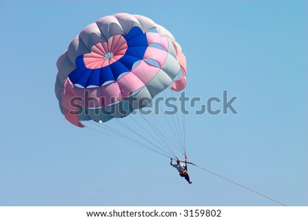 man flying on parachute in blue sky