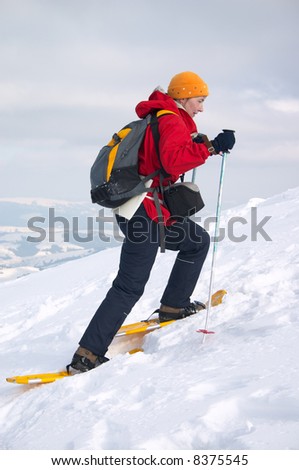 backpacker girl in snow shoes moving up on snow slope