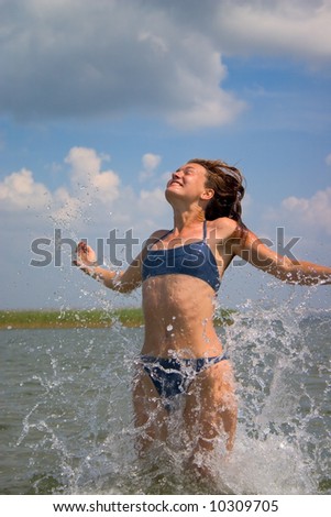 happy girl jumping in water with splashes
