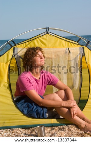 Girl sunburning in the morning near of tent at seaside