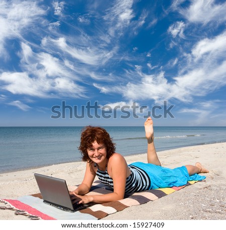 smiling girl working on laptop computer at sand sea coast