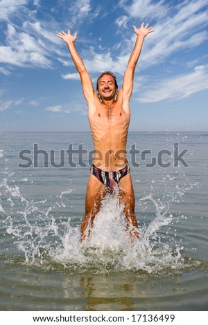 Happy man jump in sea with splashes