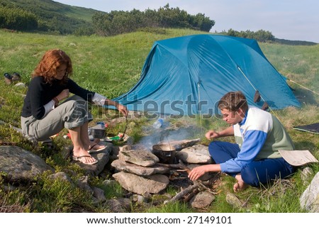 Backpackers preparing food on a fire near of a tent