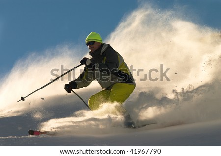 Man on ski rush at full speed in clouds of snow powder