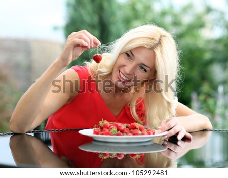 Blonde beautiful girl laughing eating and playing with fresh strawberry