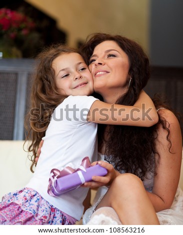 Little beautiful pretty girl giving a gift to her happy mother - indoors
