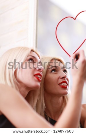 Young woman drawing heart on mirror with