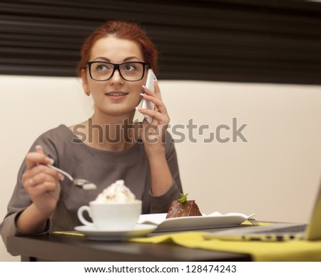 Businesswoman sitting at table in cafe using notebook. Iced coffee stands in the foreground