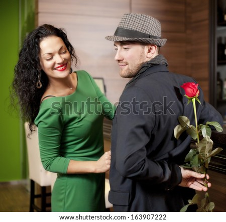 The modest young man with a rose and its girlfriend. Appointment in cafe