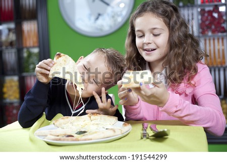 happy little girl and boy eat pizza