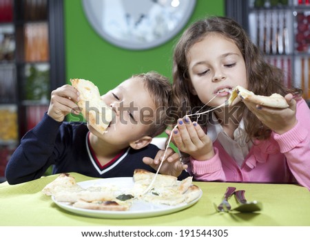 happy little girl and boy eat pizza