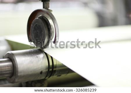 Spools of paper .Working print machine. selective focus on metal shafts and screws