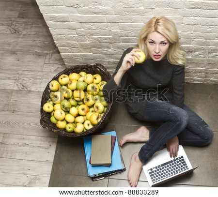Portrait of young woman with a laptop next to the basket of apples