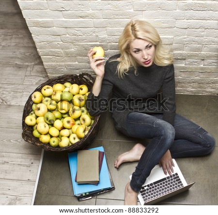 Portrait of young woman with a laptop next to the basket of apples