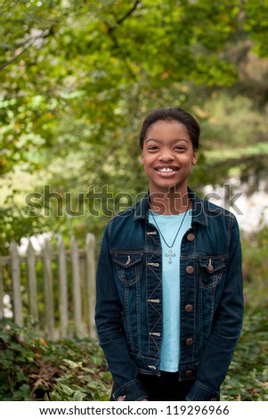 An African-American girl standing in front of an old fence in the country