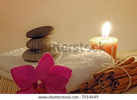 pebble stones on white towel with fired candle, cinnamon and orchid flower