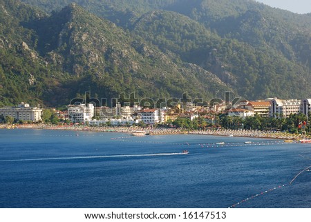 landscape of Aegean sea beach with buildings and mountains in the background