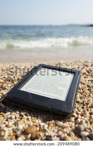 e-book reader on a beach with LOREM IPSUM text and sea i back