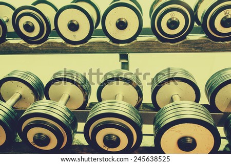 Rows of dumbbells in the gym trough an retro photo filter