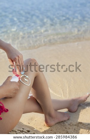 woman applying cream on her legs in a tropical ambient