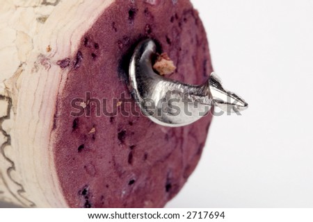 stock photo : A corkscrew piercing a red wine cork in extreme closeup