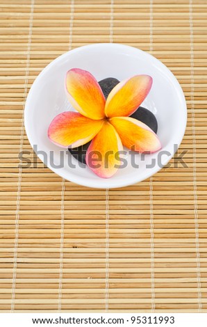 Frangipani flower in bowl with black stone