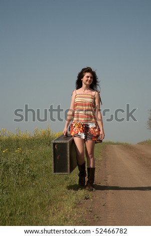 Girl with the big suitcase goes on rural road