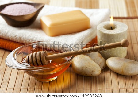 spa still life with honey, bath salt, pebbles and scented candle