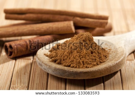 Cinnamon, Whole Sticks Behind Wooden Spoon With A Heap Of Powder
