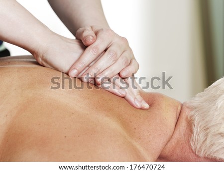 Hands of female massage therapist pressing a mid-aged woman\'s shoulders
