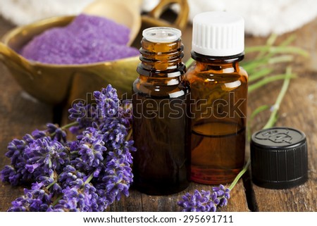 Bottles of aromatherapy essence and bath salt with lavender flowers closeup